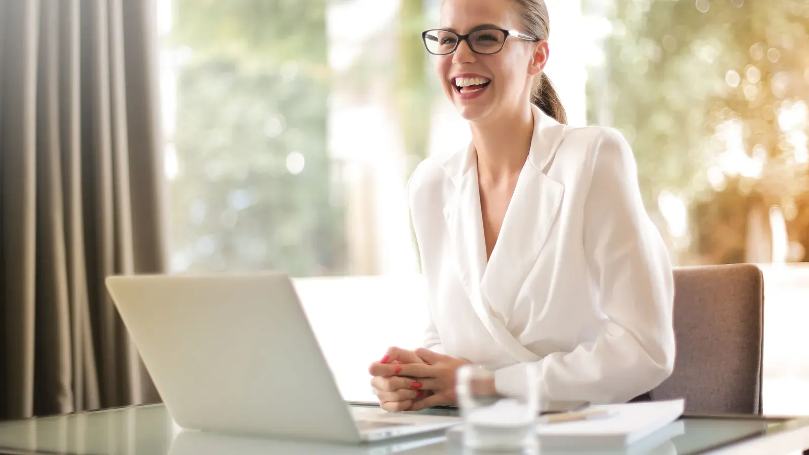 A businesswoman laughing as she works at her laptop