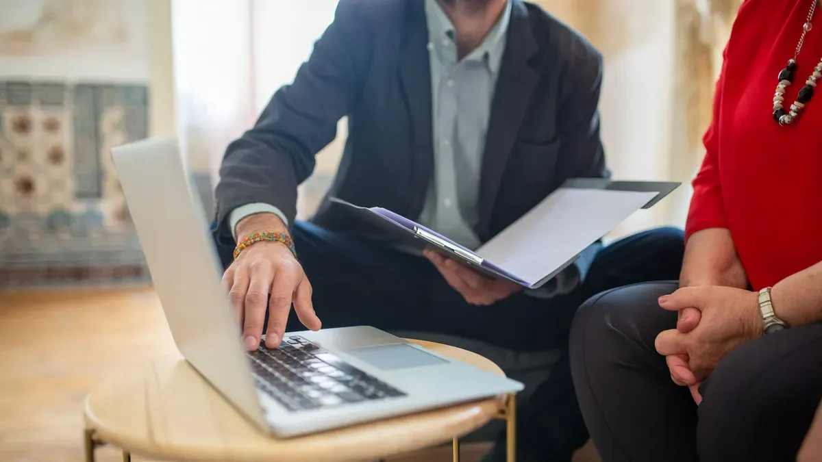 Two people going over documents together at a laptop