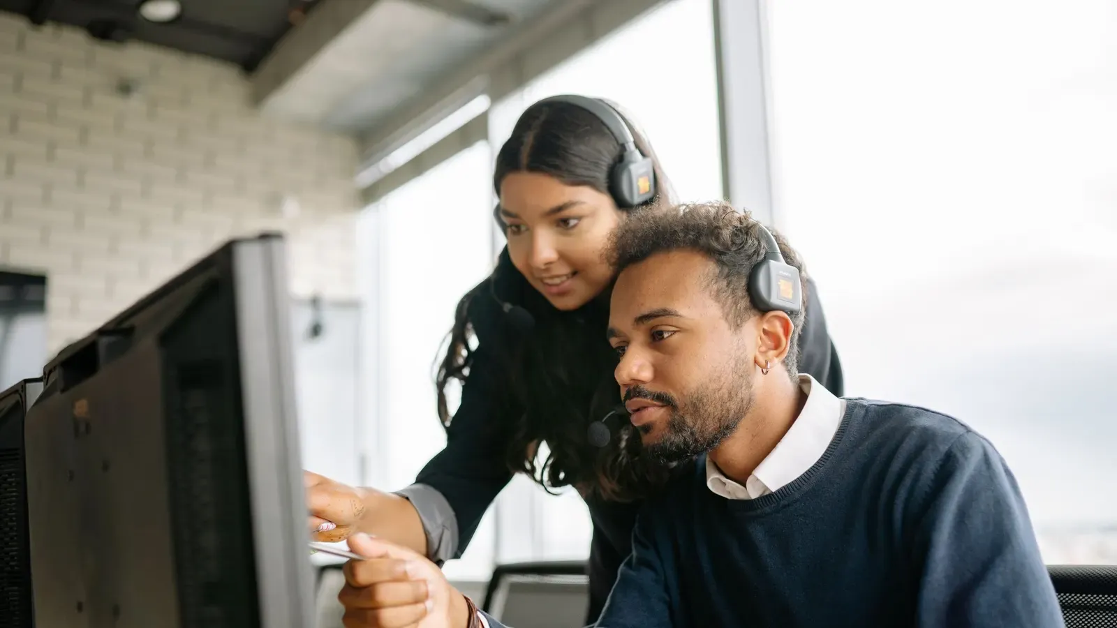 Two colleagues working through an issue at a computer